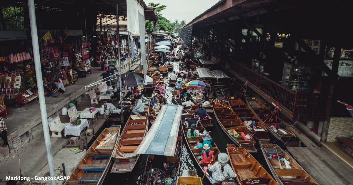 Tour boats packed together at a Thai floating market crowded with visitors